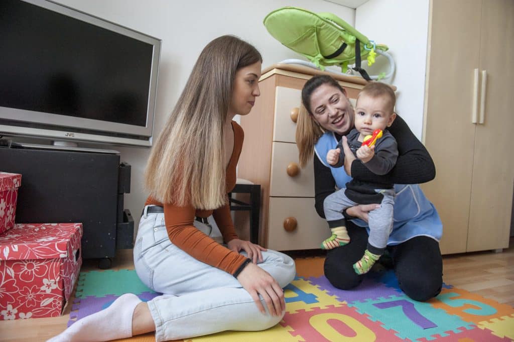 Une infirmière joue avec une mère et son enfant dans leur maison à Novi Sad, en Serbie.