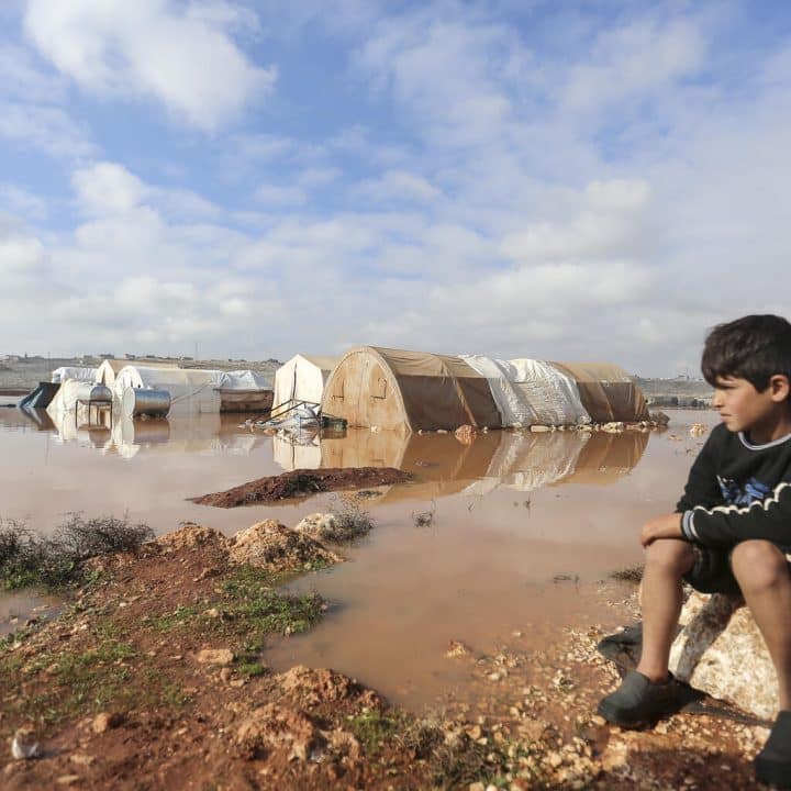 Le 19 janvier 2021, un enfant regarde une zone inondée du camp de Kafr Losin, dans le nord-ouest de la République arabe syrienne. Ces derniers jours, les gouvernorats d'Alep occidental et d'Idlib, dans le nord-ouest du pays, ont subi certaines des tempêtes hivernales les plus violentes de la saison. © UNICEF/UN0405690/Akacha