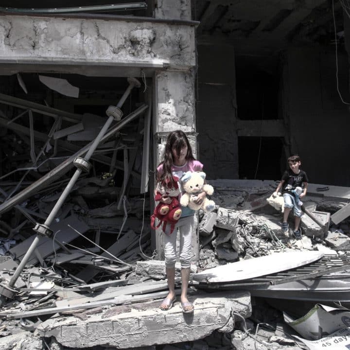 Une fille et un garçon palestiens récupèrent des objets à l'intérieur de leur maison endommagées après avoir été pris pour cible dans la ville de Gaza. © UNICEF/UN0464421/El Baba