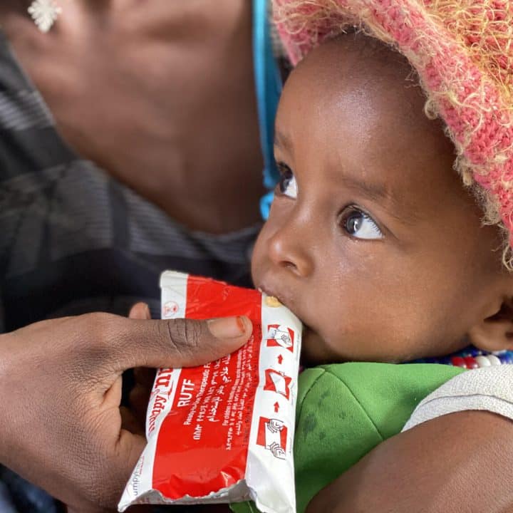 Amanuel Berhanu, tenu par sa mère, mange un peu de nourriture d'urgence après avoir subi un dépistage de la malnutrition au centre de santé Debub, dans le woreda de Wajirat, dans le sud du Tigré, en Éthiopie. UN0495650