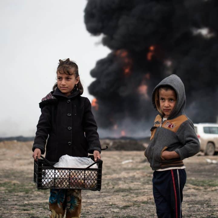 Des enfants apportent de la nourriture aux pompiers qui tentent d'éteindre des puits de pétrole incendiés par des membres d'ISIS lors de leur repli, à Qayyara, en Irak, mercredi 15 mars 2017. ©UNICEF/UN057851/Romenzi