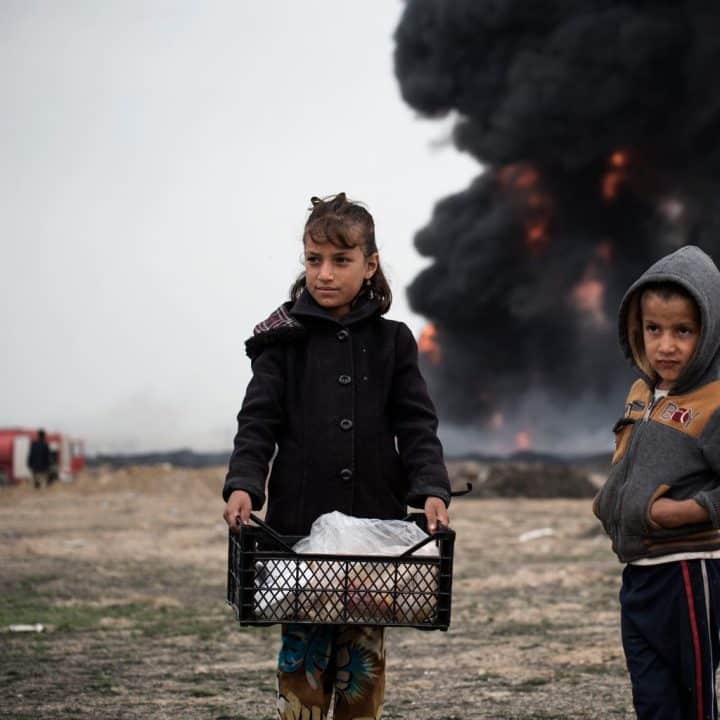 Des enfants apportent de la nourriture aux pompiers qui tentent d'éteindre des puits de pétrole incendiés par des membres d'ISIS lors de leur retraite, à Qayyara, en Irak, mercredi 15 mars 2017. © UNICEF/UN057851/Romenzi