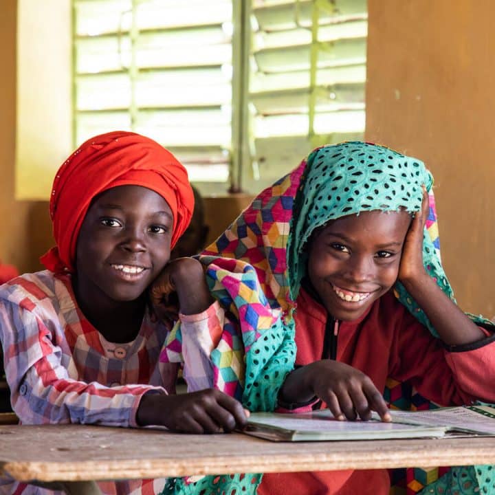 3 juenes étudiantes se rassemblent autour d'un livre dans l'école franco-arabe Diamaguene au Sénégale © UNICEF/UN0581280/Tremeau