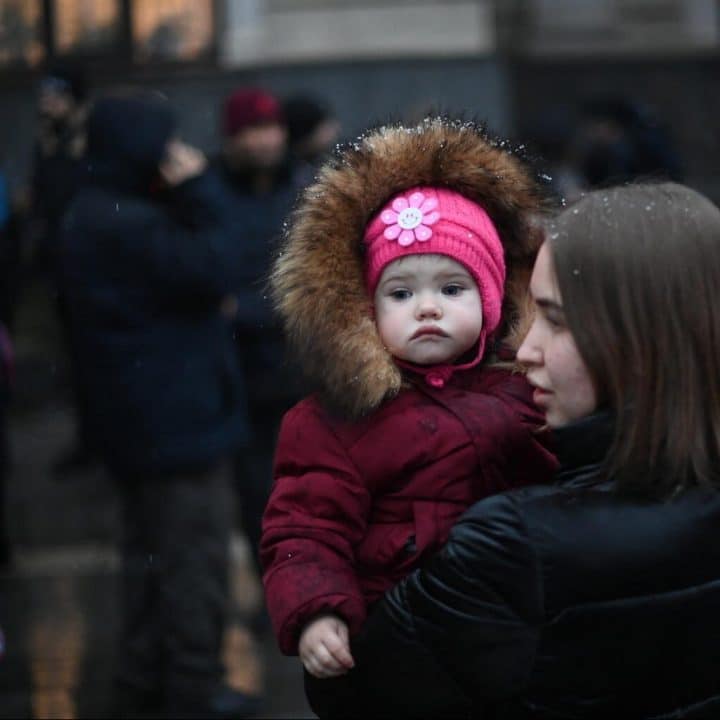 Ukraine : une jeune femme tient un enfant dans ses bras à l'extérieur d'une gare à Lviv, le 27 février 2002. ©UNICEF/UN0601051/Leal/AFP