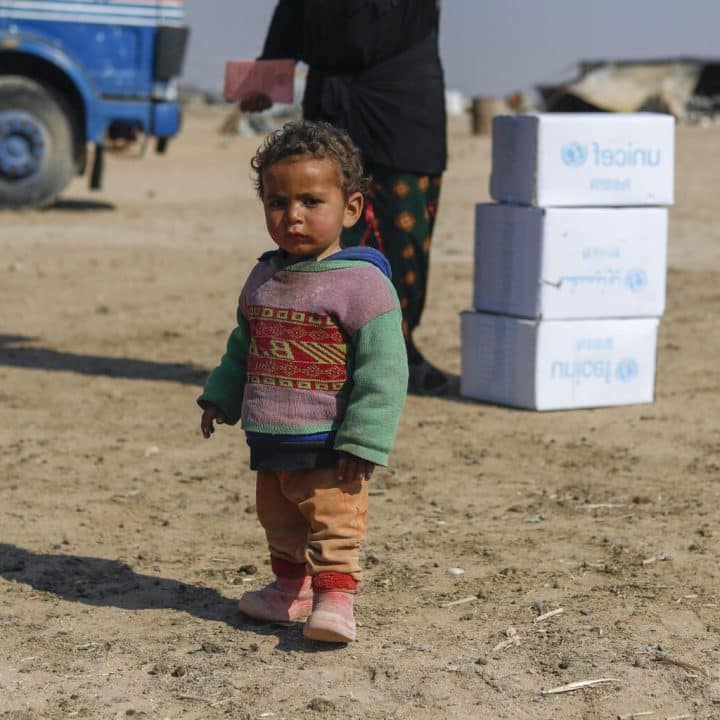 Des enfants déplacés aident leurs parents lors de la distribution de vêtements d'hiver dans le quartier informel de Kabish Wasti, à Raqqa, en Syrie, le 15 février 2022. ©UNICEF/UN0612143/Souleiman