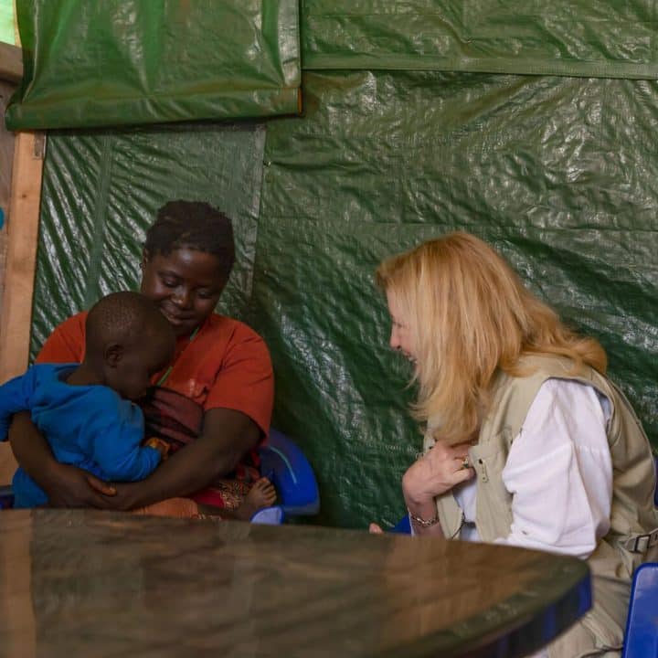 Le 5 avril 2002, en République démocratique du Congo, la directrice générale de l'UNICEF Catherine Russell s'entretient avec une mère et son enfant au camp de Rhoe pour personnes déplacées dans la province d'Ituri. ©UNICEF/UN0620997/Mulala