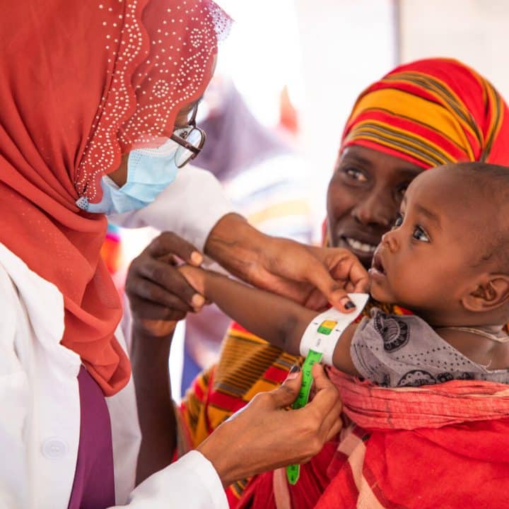 Le 26 avril 2022, à Higlo, un camp de déplacés en Éthiopie, où vivent des milliers de personnes touchées par la sécheresse, un agent de santé mesure le bras d'un enfant pour évaluer son état nutritionnel. La grave sécheresse qui sévit dans la Corne de l'Afrique pousse les communautés au bord du gouffre. Avec les pénuries alimentaires chroniques, la malnutrition est en hausse. UNICEF/UN0631314/Sewunet