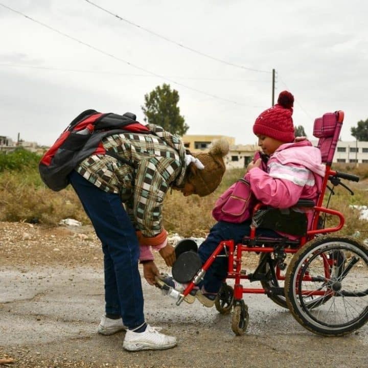 Itab, 12 ans, fixe le pied de sa sœur Nour, 11 ans, sur le marchepied alors qu'elles se rendent à l'école dans le village d'Al-Kaisa, dans la région rurale de Damas. ©UNICEF/UN0635285/Shahan