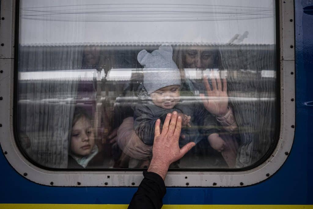 Le 20 avril 2022 à Kharkiv, en Ukraine, un homme place sa main à la fenêtre d'un wagon de train alors qu'il dit au revoir à sa femme et à ses enfants avant leur départ dans un train d'évacuation spécial. ©UNICEF/UN0637170/Gilbertson VII Photo