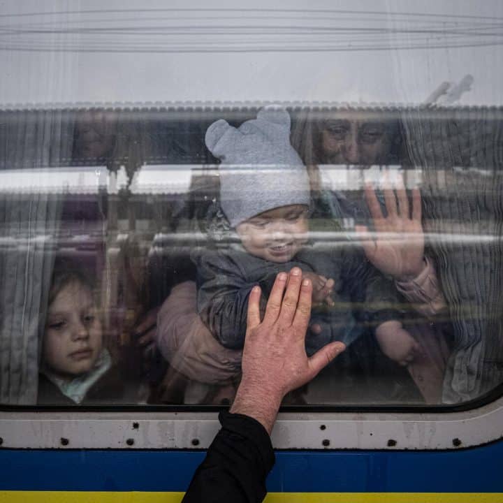 Le 20 avril 2022 à Kharkiv, en Ukraine, un homme place sa main à la fenêtre d'un wagon de train alors qu'il dit au revoir à sa femme et à ses enfants avant leur départ dans un train d'évacuation spécial. ©UNICEF/UN0637170/Gilbertson VII Photo