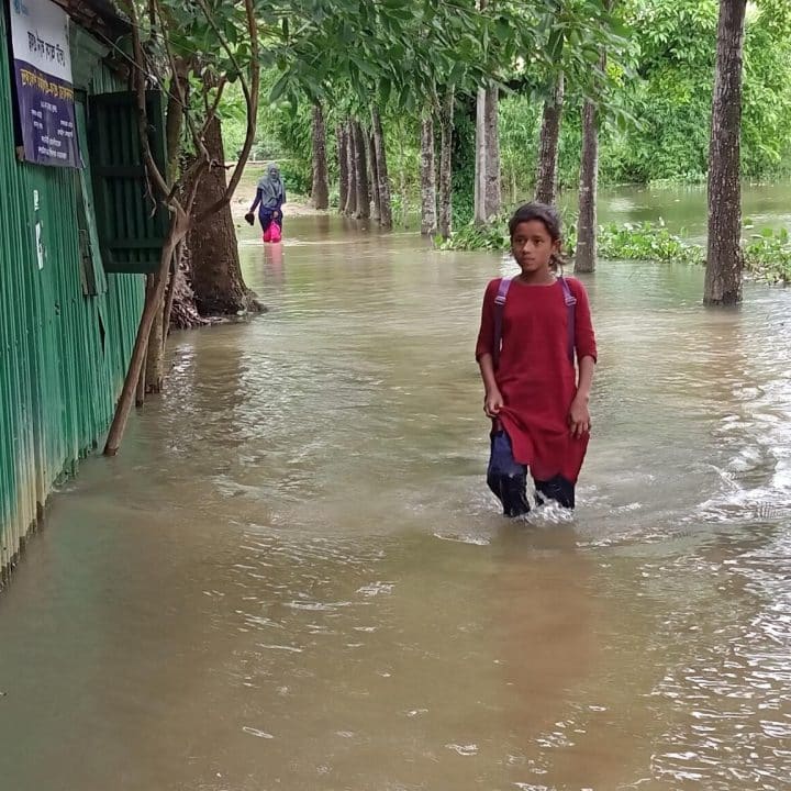 Resma Begum, une élève d'une école soutenue par l'UNICEF à Sunamganj, inondée lors des fortes inondations du nord-est du Bangladesh, se fraie un chemin à travers les eaux de crue pour se rendre en classe le 17 mai 2022. © UNICEF/UN0641538/Begum