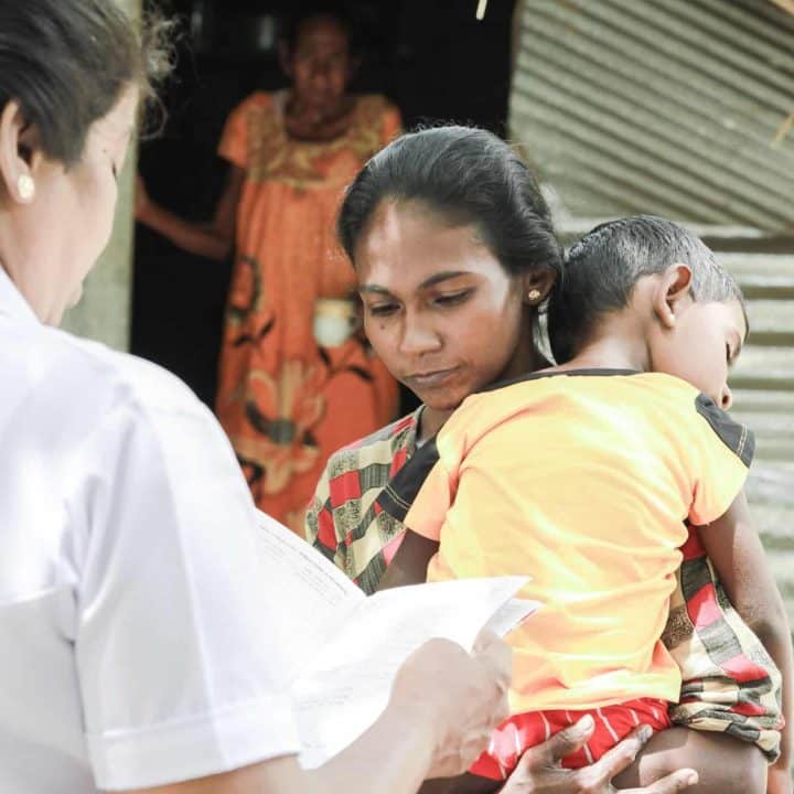 Le 5 juillet 2022, tenant dans ses bras son enfant de 3 ans qui souffre de malnutrition, Selvathy parle à la sage-femme du village de Devapuram, dans le district sri-lankais de Batticaloa. ©UNICEF/UN0670388/Weerasinghe