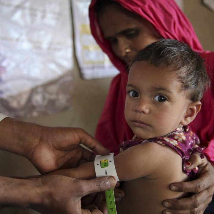 Pakistan, 2012. Un agent de santé vérifie la situation nutritionnelle d'un enfant en utilisant la méthode du périmètre brachial dans un centre de santé mobile soutenu par l'UNICEF dans le village de Pyaro Khoso, district de Badin, province de Sindh. ©UNICEF/UNI151819/Zaidi