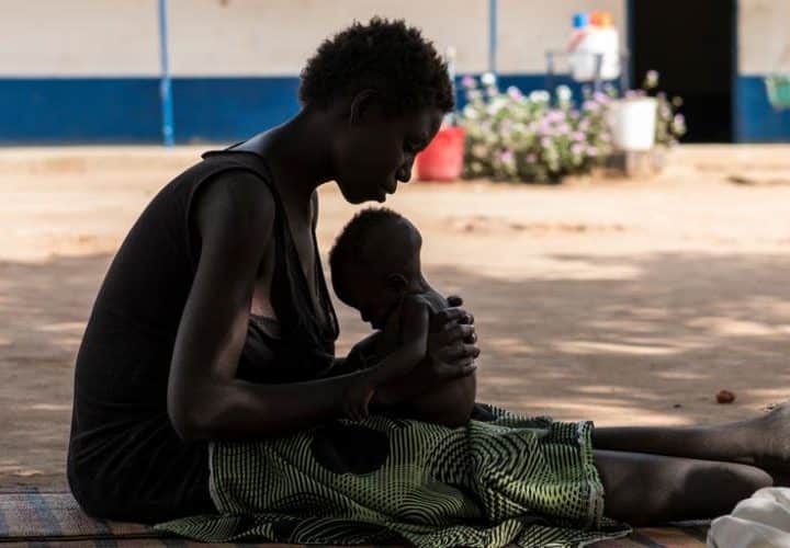 Une jeune maman porte son enfant souffrant de malnutrition dans un centre de soin soutenu par l'UNICEF au Soudan du Sud
