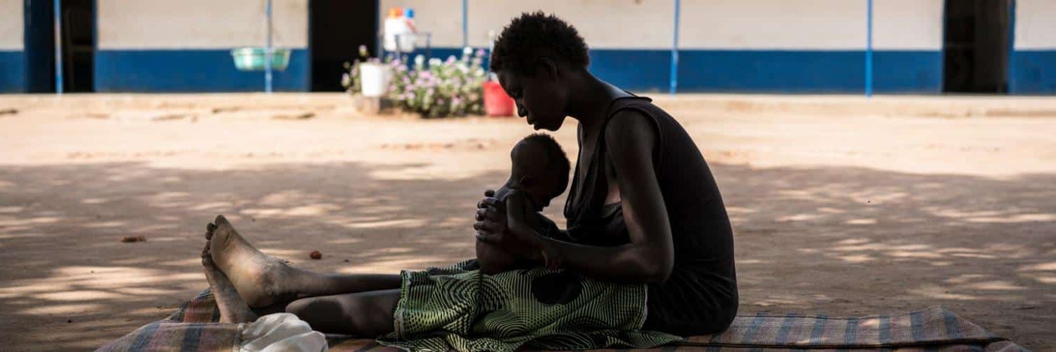 Une jeune maman porte son enfant souffrant de malnutrition dans un centre de soin soutenu par l'UNICEF au Soudan du Sud.