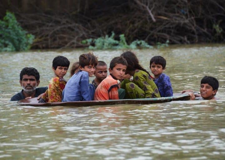 Le 26 août 2022, un homme et un jeune garçon se servent d'une antenne parabolique pour faire traverser aux enfants une zone inondée après de fortes pluies de mousson dans le district de Jaffarabad, dans la province du Baloutchistan, au Pakistan. ©UNICEF/UN0698138/Hussain/AFP