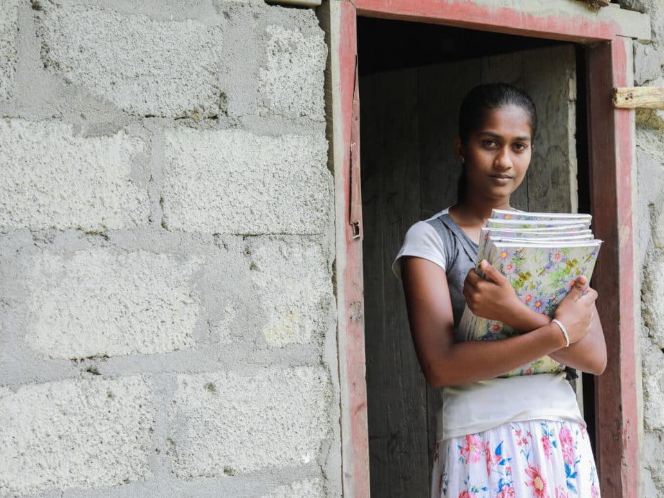 Le 6 juillet 2022, Dilrukshi, 15 ans, pose pour une photo en tenant ses livres devant sa maison à Kohombagasthalawa, au Sri Lanka. © UNICEF/UN0671046/Weerasinghe