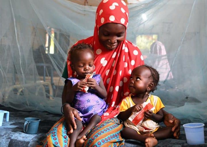 Nana Hadiza, 28 ans, tient ses jumelles dans ses bras alors qu'elles sont assises sur un lit d'hôpital au CHU de Maradi, au Niger. Les jumelles sont traitées pour malnutrition avec des aliments thérapeutiques prêts à l'emploi. ©UNICEF/UN0535873/Dejongh