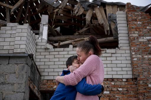 Le 15 avril 2022, en Ukraine, Olena tient son fils, Mikhailo, dans ses bras et l'embrasse, devant leur maison endommagée de Novoselivka, près de Tchernihiv. © UNICEF/UN0632758/Gilbertson VII Photo