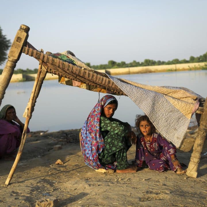 Le 10 septembre 2022, réfugiées sur le bord de la route dans le district de Jacobabad, dans la province de Sindh, Bahira, 11 ans, Fozia, 5 ans, et leur mère Rukhsar, sont assises près des eaux de crue, après avoir fui leur maison touchée par les inondations. ©UNICEF/UN0702907/Zaidi