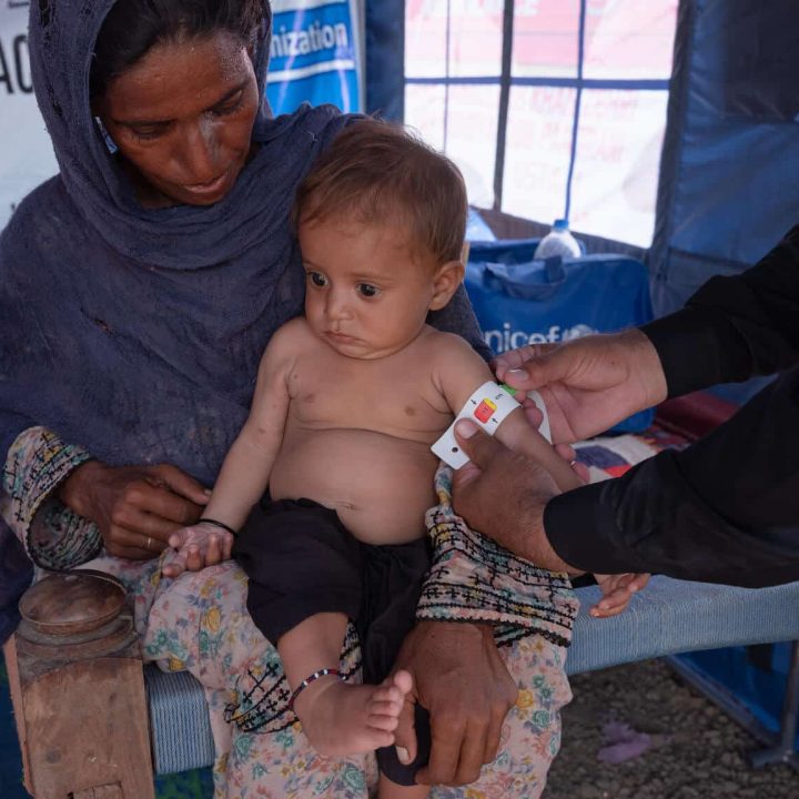Le 14 septembre 2022, un médecin vérifie l'état nutritionnel de Naqibullah, six mois, qui souffre de malnutrition et est traité avec des aliments thérapeutiques prêts à l'emploi (RUTF) fournis par l'UNICEF, pendant qu'il est assis sur les genoux de sa mère Nazira. © UNICEF/UN0717123/d'Aki