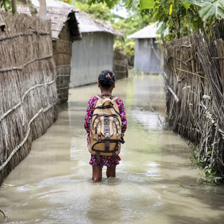 Une enfant traverse l'eau en pataugeant sur le chemin de l'école dans le district de Kurigram, dans le nord du Bangladesh, pendant les inondations d'août 2016. © UNICEF/UN0286416/Akash