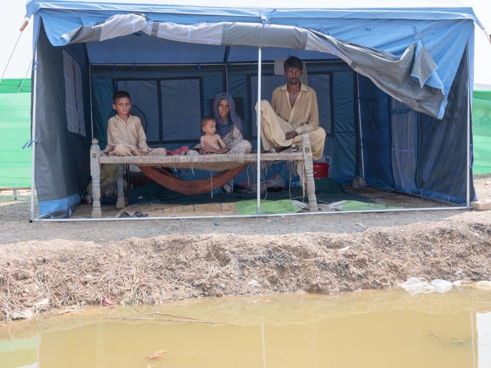 Hassan, sa femme Nazira avec son fils de 6 mois, Naqibullah, sur ses genoux, Shoaib, 18 mois, couché, et Nasir Ahmed, 8 ans, sont dans une tente de fortune dans un camp temporaire suite aux inondations au Pakistan. Photo prise le 14 septembre 2022.