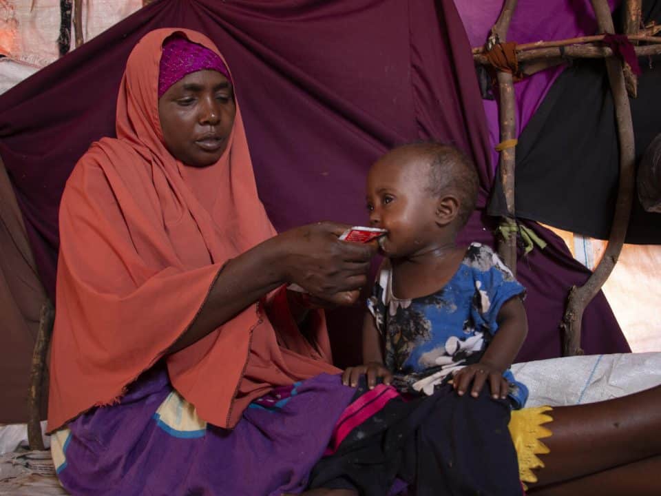 Le 21 septembre 2022, Khadijo nourrit sa fille Sabirin, âgée de deux ans, avec des aliments thérapeutiques prêts à l'emploi (RUTF) dans leur maison de fortune, dans un camp de personnes déplacées de Gurman, dans la banlieue de Mogadiscio, en Somalie. © UNICEF/UN0719418/Yusuf