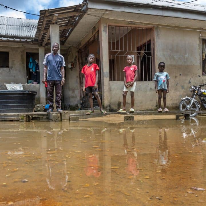 Germany se tient devant leur maison inondée à Indiamazi, Sagbama, Bayelsa State au Nigéria, avec 3 de ses enfants. Photo prise le 4 octobre 2022.