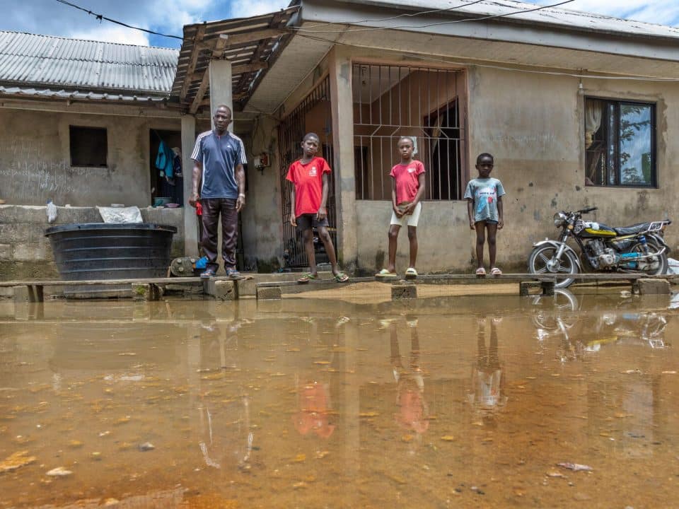 Germany se tient devant leur maison inondée à Indiamazi, Sagbama, Bayelsa State au Nigéria, avec 3 de ses enfants. Photo prise le 4 octobre 2022.