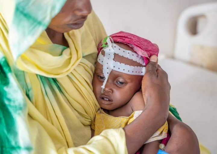 Le 27 octobre 2022 au Puntland, en Somalie, Aisha Mohamed, âgée d'un an, est tenue par sa mère, Isniino Ali, alors qu'elle est traitée pour malnutrition aiguë sévère au centre de stabilisation de l'hôpital général de Garowe. ©UNICEF/UN0750315/Ekpu VII Photo