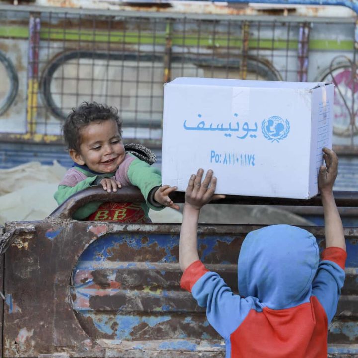 Des enfants déplacés aident leurs parents lors de la distribution de vêtements d'hiver dans le quartier informel de Kabish Wasti, à Raqqa, en Syrie, le 16 février 2022. © UNICEF/UN0612169/Souleiman