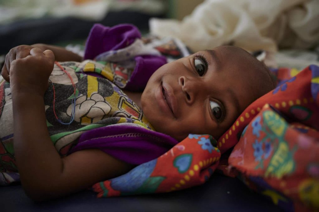 Ali Abubakar sourit alors qu'il se remet de la malnutrition sévère à l'hôpital de Damazin, soutenu par l'UNICEF, à Ad-Damazin, au Soudan. © UNICEF/UNI236401/Noorani