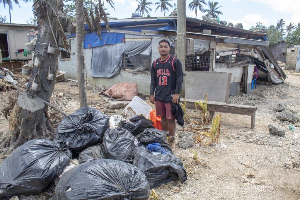 Le 22 janvier 2022, Sione, 18 ans, se tient devant sa maison à Sopu sur Tongatapu, l'île principale de Tonga, montrant les dégâts causés par l'éruption du volcan sous-marin Hunga Tonga-Hunga Ha'apai et le tsunami. © UNICEF/UN0582133/Wolfgramm