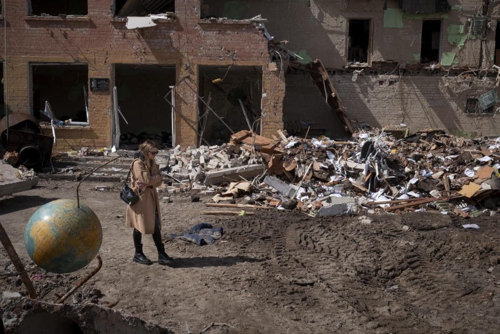 Le 14 avril 2022 à Tchernihiv, en Ukraine, Katya, 24 ans, marche dans les décombres de l'école numéro 21, qui servait d'abri civil et de base logistique avant d'être détruite par une frappe aérienne, qui a fait de nombreuses victimes. © UNICEF/UN0632567/Gilbertson VII Photo