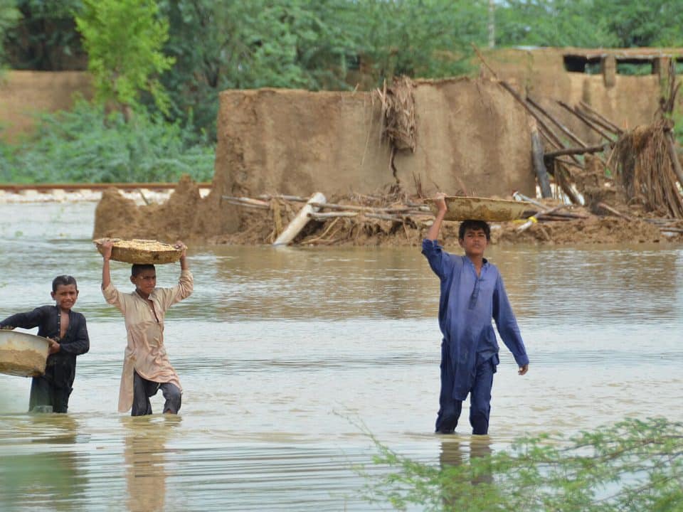 Le 26 août 2022, des garçons transportent de la nourriture alors qu'ils pataugent dans une zone touchée par les inondations après de fortes pluies de mousson dans le district de Jaffarabad, dans la province du Baloutchistan, au Pakistan.