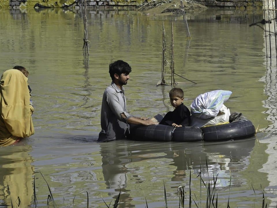 Le 26 août 2022, une famille traverse une zone inondée à la suite de fortes pluies de mousson dans le district de Charsadda de la province de Khyber Pakhtunkhwa, au Pakistan. © UNICEF/UN0698139/Majeed/AFP