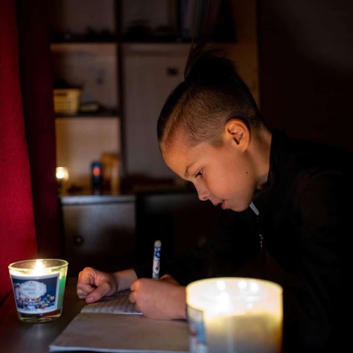 À la lumière vacillante d'une bougie, Timofiy, 11 ans, fait ses devoirs. Bucha, Ukraine, 27 novembre 2022. © UNICEF/UN0755379/Filippov