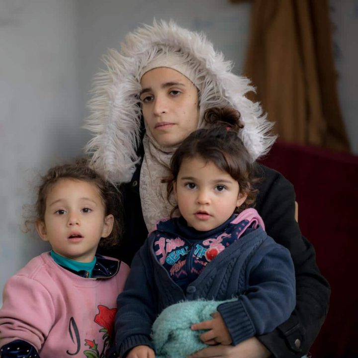 Le 15 février 2023, en Syrie, Aalaa tient dans ses bras ses filles, Ritaj (à gauche), âgée de 3 ans, et Mona, âgée de 4 ans, alors qu'elle est assise dans une salle de l'école Jihad Kheirbeik du district de Jableh, dans le gouvernorat de Lattaquié, qui sert d'abri temporaire pour les personnes déplacées de leurs maisons par le récent tremblement de terre. © UNICEF/UN0784068/Haddad