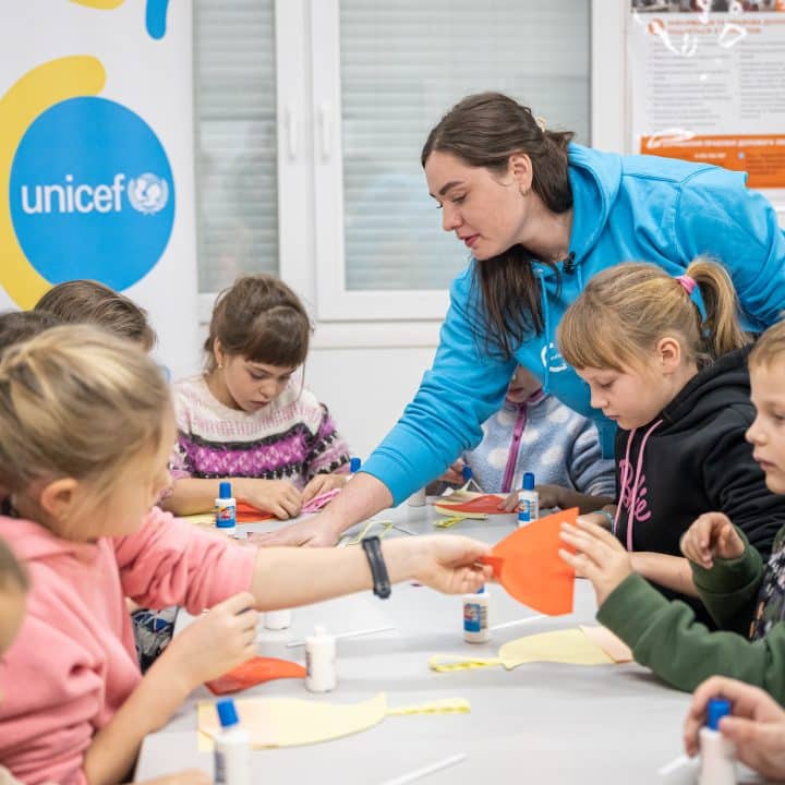 Le 14 décembre 2023, l'assistante sociale Krystyna montre aux enfants comment fabriquer une décoration de Noël. Une centaine de familles vivent aujourd'hui dans le village pour personnes déplacées de Pavlohrad en Ukraine. Les enfants reçoivent l'aide de l'assistante sociale et de la psychologue qui fond partie d'une équipe de spécialistes soutenus par l'UNICEF © UNICEF/UNI517456/Lebid