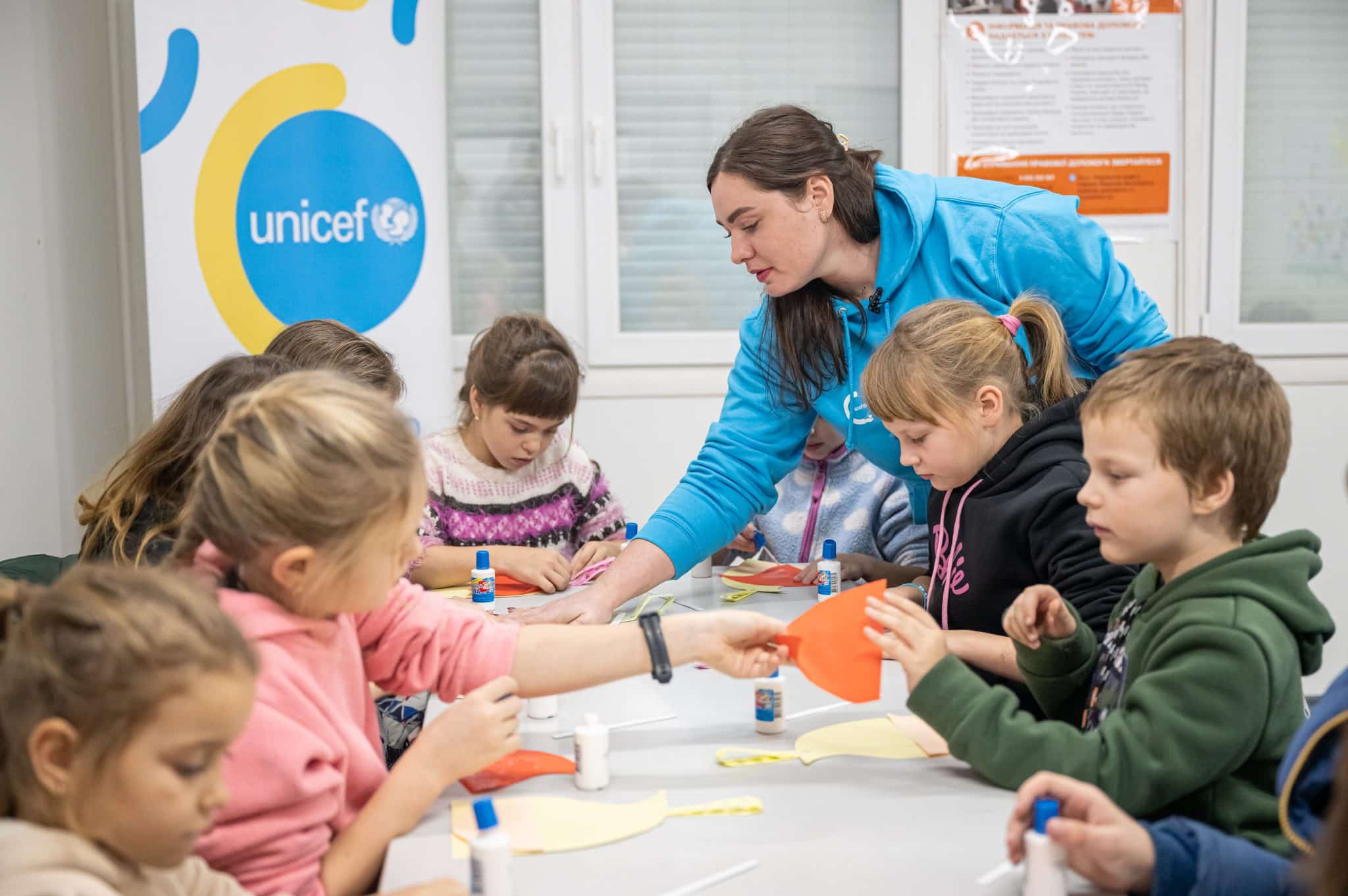 Le 14 décembre 2023, l'assistante sociale Krystyna montre aux enfants comment fabriquer une décoration de Noël. Une centaine de familles vivent aujourd'hui dans le village pour personnes déplacées de Pavlohrad en Ukraine. Les enfants reçoivent l'aide de l'assistante sociale et de la psychologue qui fond partie d'une équipe de spécialistes soutenus par l'UNICEF © UNICEF/UNI517456/Lebid