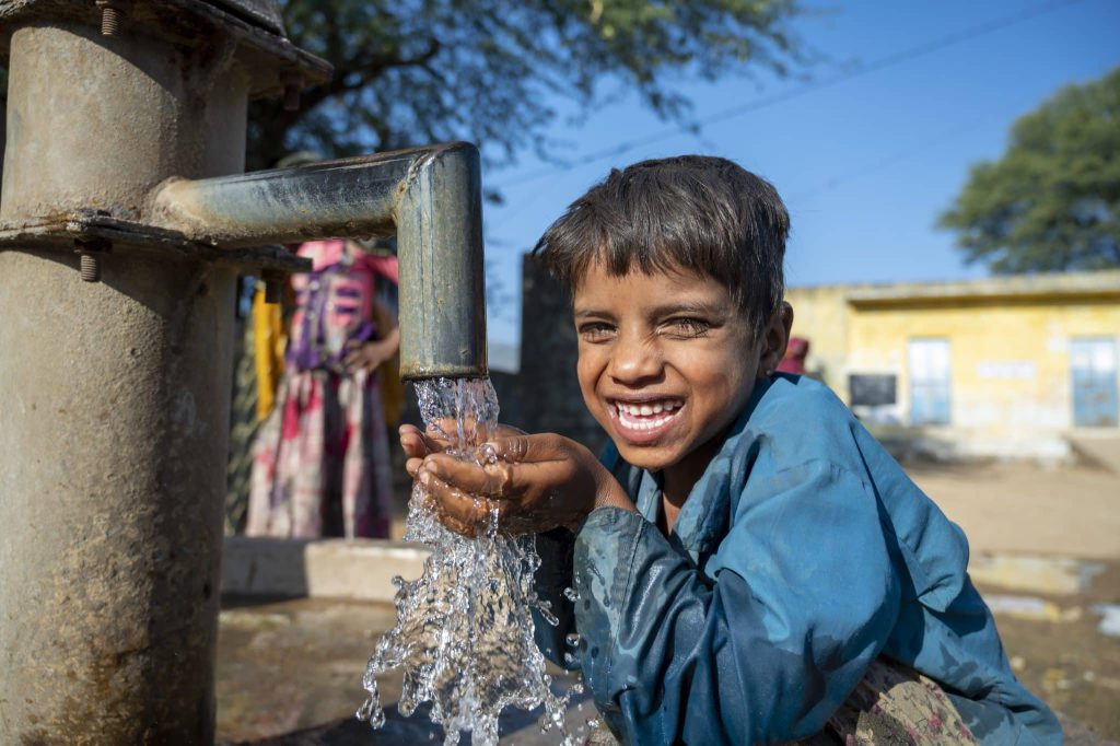 [Accès à l'eau potable] Photo d'un jeune garçon heureux d'avoir accès à la pompe à eau du village Mata Devi, en Inde. © UNICEF/UN0389249/Panjwani