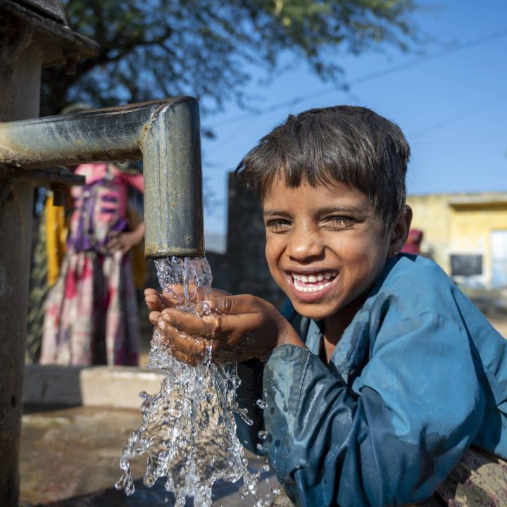 Photo d'un jeune garçon heureux d'avoir accès à la pompe à main du village Mata Devi, Abu Road, Rajasthan, en Inde. © UNICEF/UN0389249/Panjwani