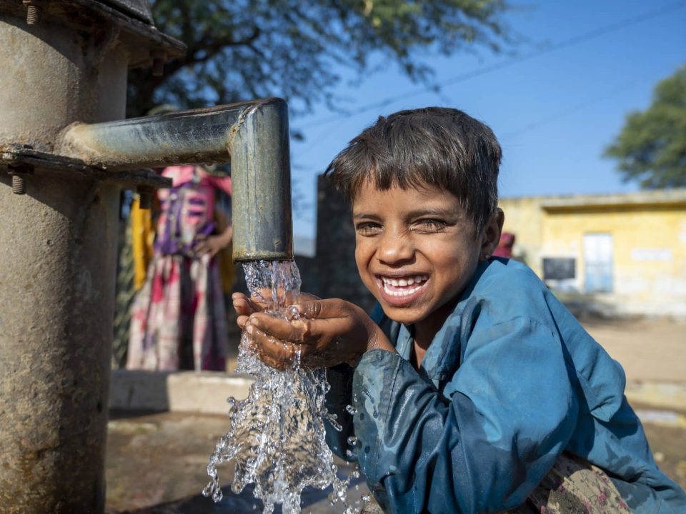 Photo d'un jeune garçon heureux d'avoir accès à la pompe à main du village Mata Devi, Abu Road, Rajasthan, en Inde. © UNICEF/UN0389249/Panjwani