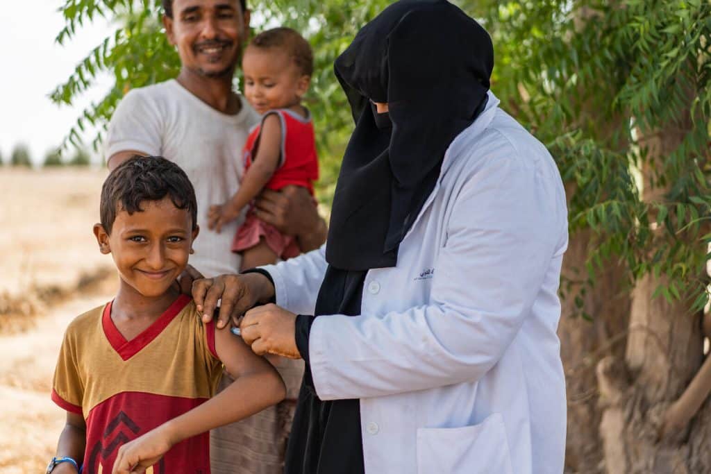 Le 6 juin 2022, dans le gouvernorat d'Aden, au Yémen, Ghada, 53 ans, agent de santé, vaccine Hamza, 10 ans, lors d'une campagne de vaccination pour les enfants. © UNICEF/UN0679327/Hayyan