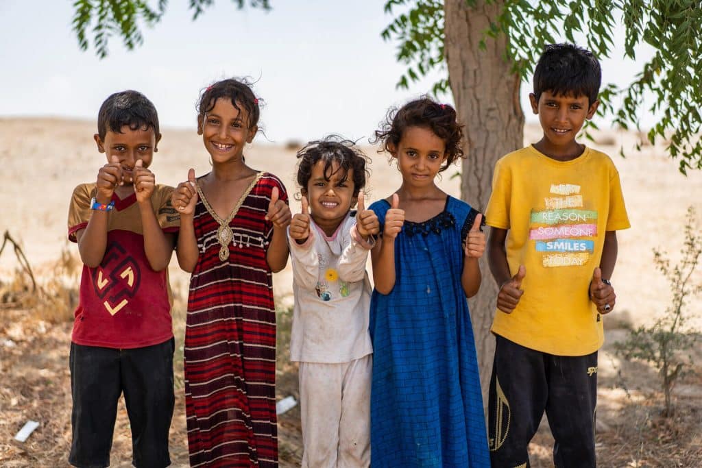 Le 6 juin 2022, dans le gouvernorat d'Aden, au Yémen, Hamza (chemise rouge), 10 ans, Amani (robe rouge), 11 ans, Hind (robe bleue), 7 ans, et deux autres enfants, lèvent le pouce après avoir été vaccinés lors d'une campagne de vaccination pour les enfants. © UNICEF/UN0679352/Hayyan