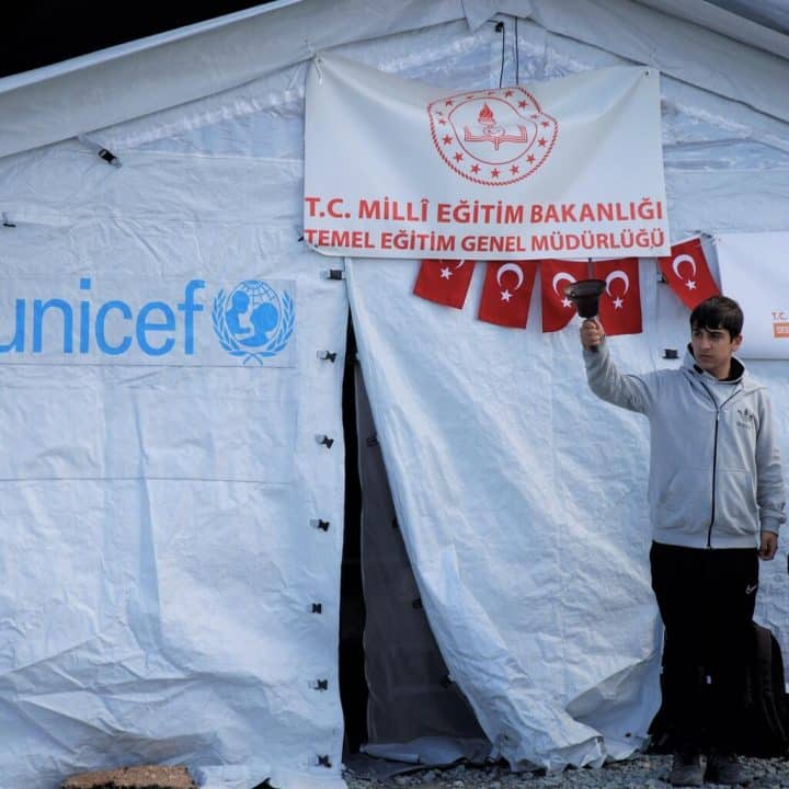 Deux enfants se tiennent devant une salle de classe provisoire installée sous une tente par l'UNICEF à Antakya, en Turquie. ©UNICEF/UN0801736/Karacan