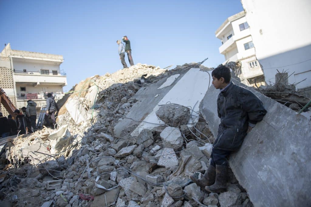 Un garçon du quartier de Rumaila dans la ville de Jableh, gouvernorat de Lattaquié, dans le nord-ouest de la République arabe syrienne, observe les travaux d'excavation suite au tremblement de terre qui a frappé sa ville. © UNICEF/UN0779763/Belal