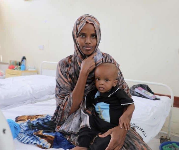 Mansuur Osman attend dans les bras de sa mère, Harira Adow, au centre de stabilisation de l'hôpital de référence du comté de Garissa. Il se remet d'une malnutrition aiguë sévère causée par la sécheresse prolongée. ©UNICEF/UN0836010/Odhiambo