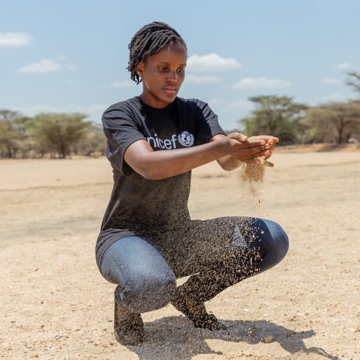 Kenya, 9 septembre 2022 : la militante ougandaise pour le climat Vanessa Nakate, ambassadrice de l’UNICEF, âgée de 25 ans, prend une poignée de terre séchée dans ce qui reste de la rivière Sopel. ©UNICEF/UN0702759/Translieu/Nyaberi